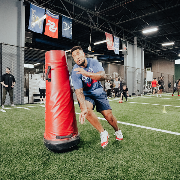 An athlete running around a obstacle on an indoor turf.