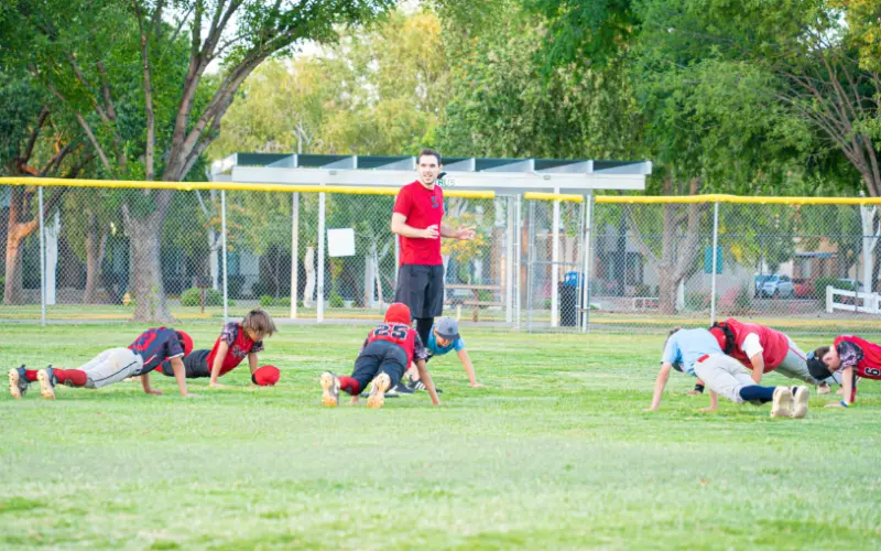 A group of kids planking on a grassy field.