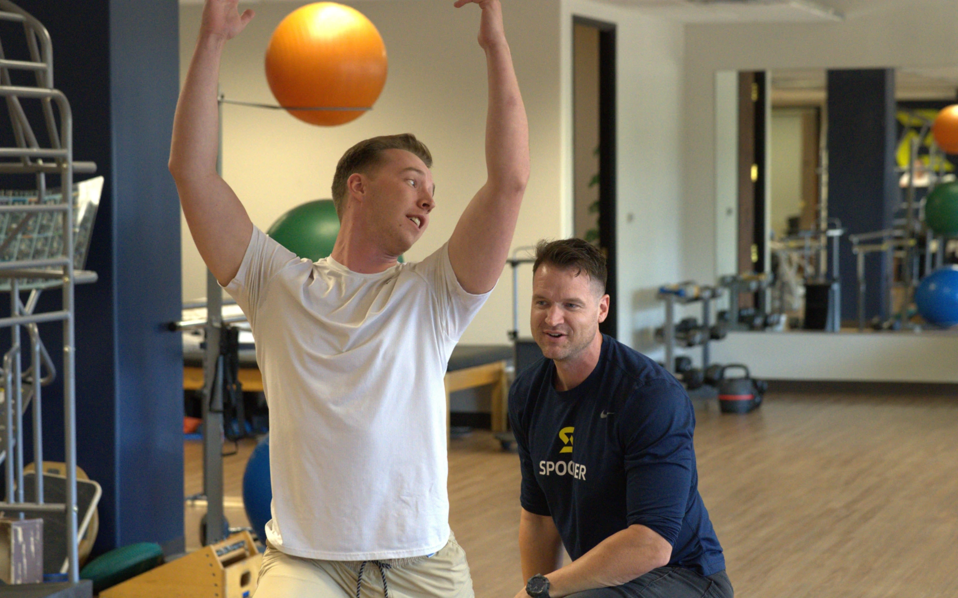 Ryan Neslund, PT, DPT, CSCS, Cert, VRS coaches a male patient on the planes of motion as the patient reaches into the air at the Spooner Biltmore clinic.