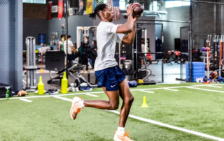 A college football player catching a football on an indoor green.