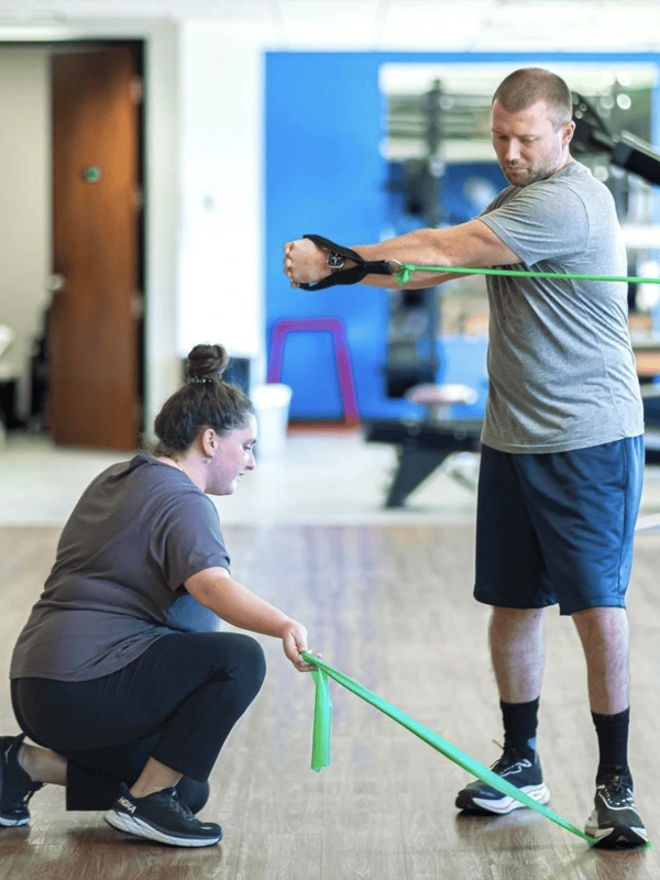 A man twisting as he holds a tension band in his left and and hold another tension band down with his left foot.