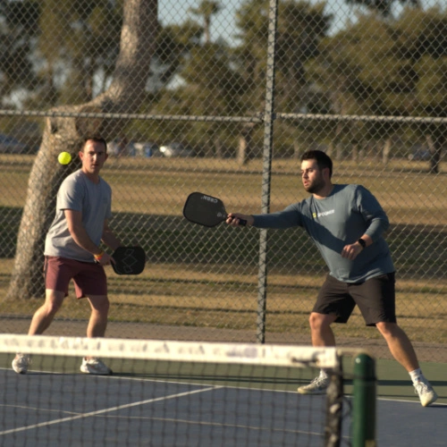 Two men playing pickleball outside.