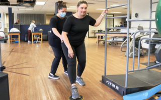 A female patient training her kegels with a slip pad as a physical therapist stabilizes her hip.