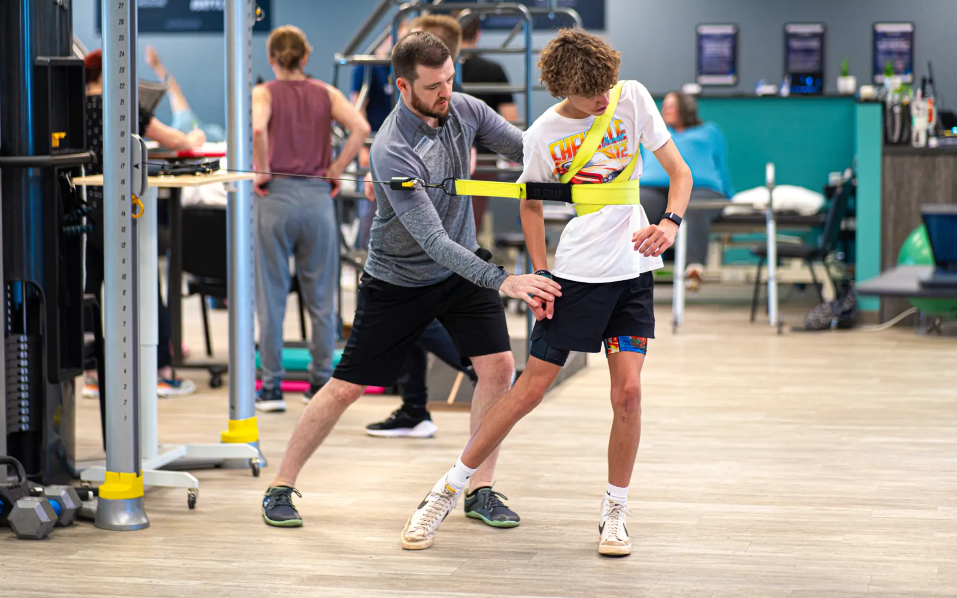 Matt Getz, PT, DPT, FAFS helps a young male athlete do a hip rotation with a cable machine at the Spooner North Mesa clinic.