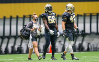 Kaitlyn Keyser on the field with Saints team football players.