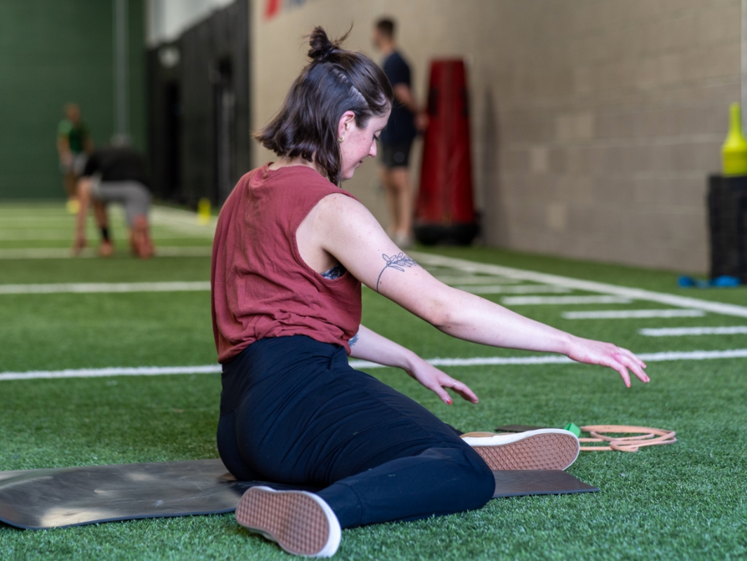 Image of a woman doing the 90/90 exercise in the end position facing right.