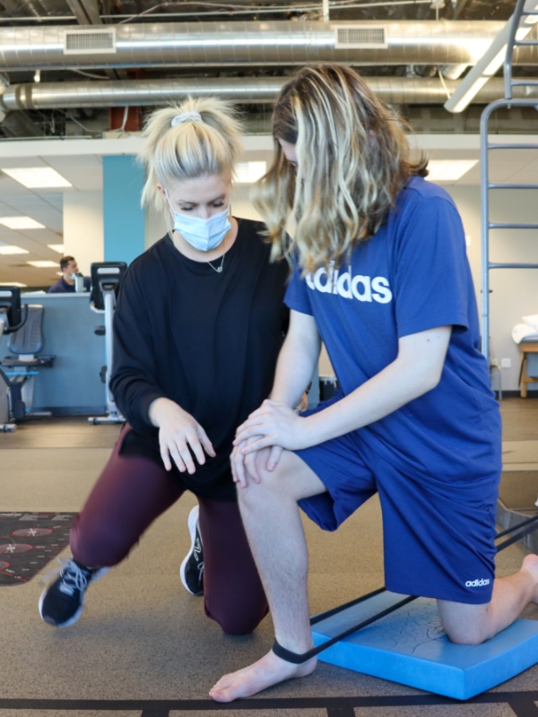 Image of a teen kneeling with a tension band around his leg.