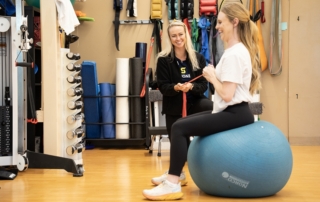 Feature image of a woman on a bosu ball stretching with a rubber band.