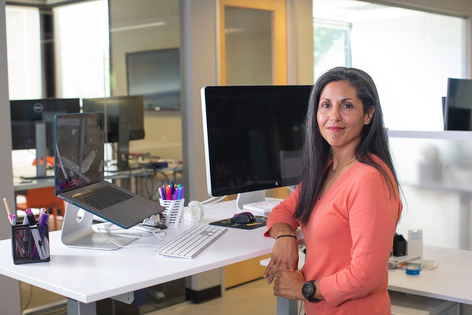 Woman posing with her elbow on her standing desk.